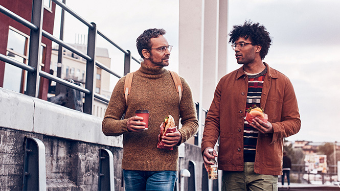 Two friends walking holding foot and drink from Circle K