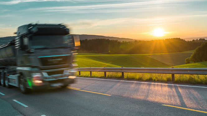 Truck driving along a motorway at sunset