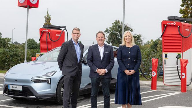 Three people in front of a electric car being charging at a CK station