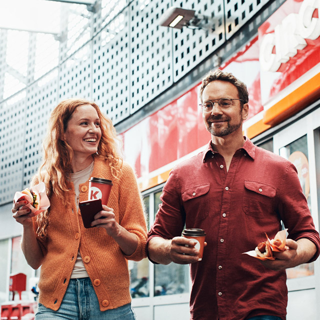 A woman and a man at Circle K carrying coffee and snacks